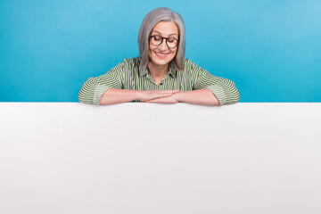 Photo of middle aged grandmother hands folded arms looking down presentation placard brand cheap online service isolated on blue color background © deagreez