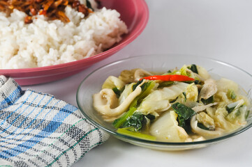 mustard greens and mushrooms are served on a small plate, white rice with anchovy and a napkin isolated on a white background