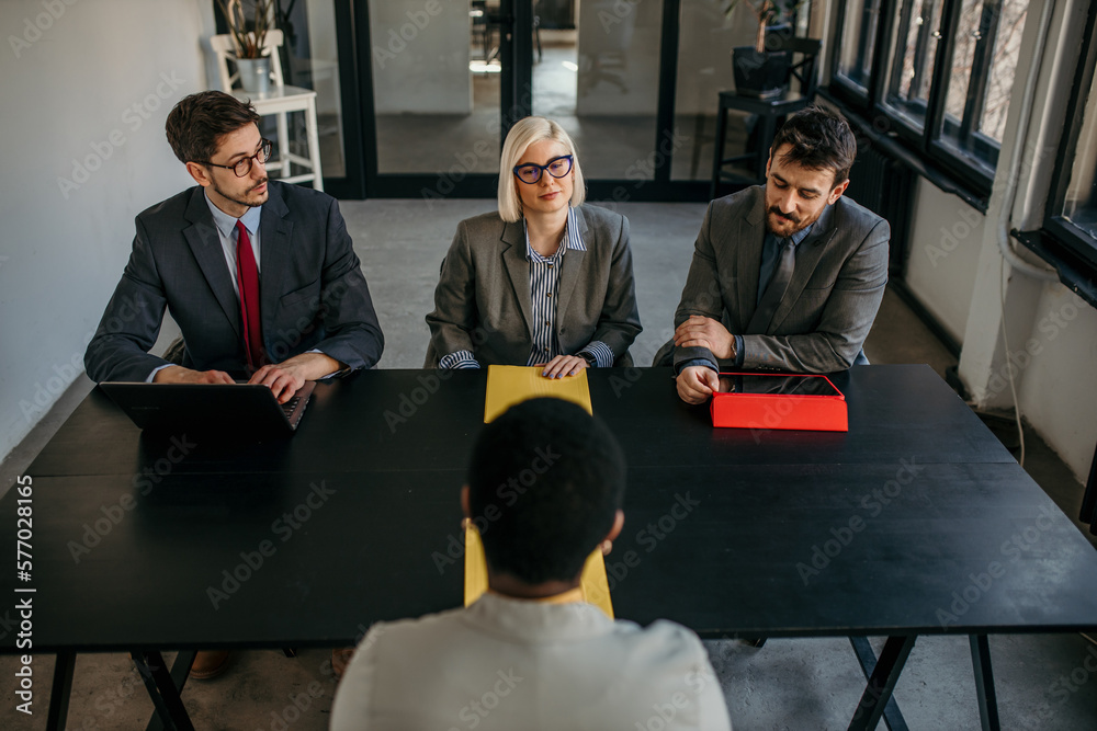 Wall mural female candidate talking to human resource team while giving them application forms on a job intervi