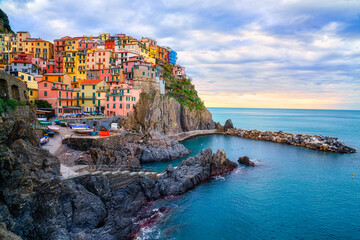 Stunning view of Manarola village in Cinque Terre National Park, beautiful cityscape with colorful houses and green terraces on cliffs over a sea, Liguria region of Italy. Outdoor travel background - obrazy, fototapety, plakaty