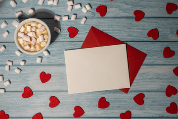 Greeting or invitation card mock up with red envelope with white cup of coffee and marshmallows on wooden background. Romantic Small hearts Valentine day. Blank paper card copy space for your text