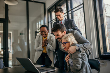 Shot of a group of young businesspeople using a laptop and receiving great news in a modern office.
