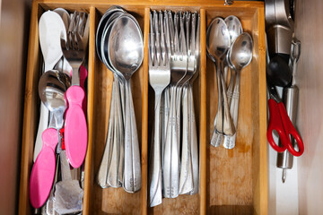 Clean and silver spoons, forks at kitchen drawer with cutlery set. Flat lay view of organizer tray...