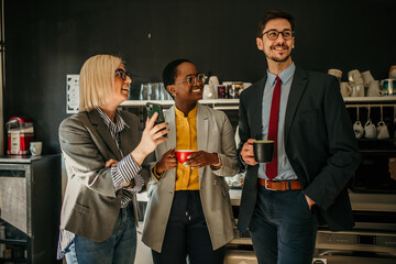 Multi-ethnic group of business people chilling and laughing while talking to each other and using the phone on a break in the office