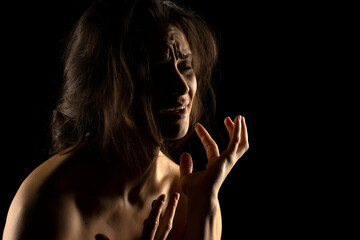 Silhouette of young unhappy crying woman on black background