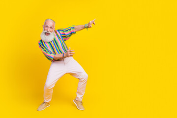 Full length photo of impressed positive guy dressed striped shirt dancing disco empty space isolated yellow color background