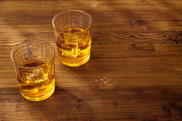 Glass of golden whiskey with ice. Strong alcoholic drink background