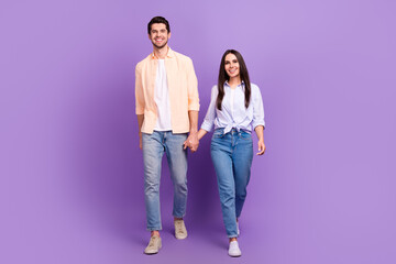 Fototapeta premium Full body photo of two cheerful nice partners hold arms walking good mood isolated on violet color background