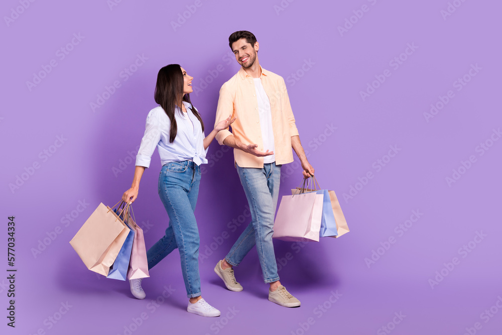 Poster full body profile photo of two cheerful friendly partners walk hold bags speak chatting empty space 