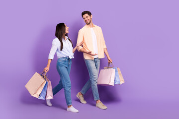 Full body profile photo of two cheerful friendly partners walk hold bags speak chatting empty space...