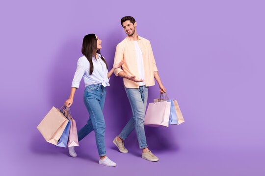 Full Body Profile Photo Of Two Cheerful Friendly Partners Walk Hold Bags Speak Chatting Empty Space Isolated On Violet Color Background