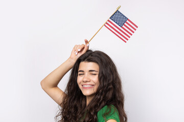 A young happy girl with a smile on her face holds an American flag in her hands. Symbol of patriotism and freedom.