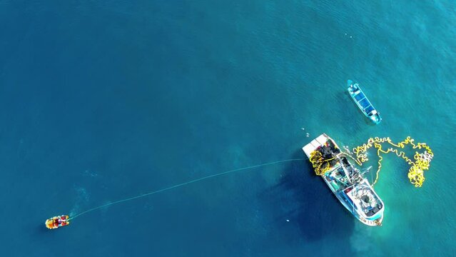 Aerial View Of Fishing Boat Picking Up Its Fishing Net In The Open Sea