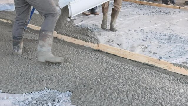 An concrete mixing truck pour out concrete for pavement around new house