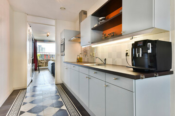 a kitchen area with black and white tiles on the floor, along with an open door leading to another...