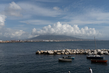 Fototapeta na wymiar Local fishing boats at a small port and Vesuvius volcano in the background