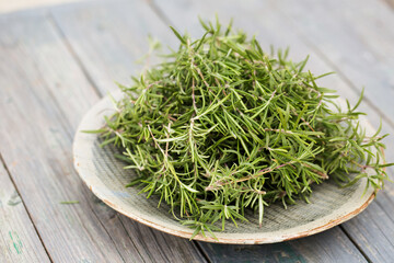 aromatic rosemary in a gray bowl on a wooden background
