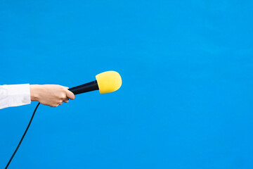 holding a yellow microphone with copy space, interview concept.