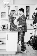 a pregnant woman and a man in pajamas in the kitchen