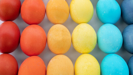 Easter eggs background. The eggs are painted in the same colors of the rainbow and laid out in a gradient on a white background. Happy easter eggs in minimal style close up photo with copy space.