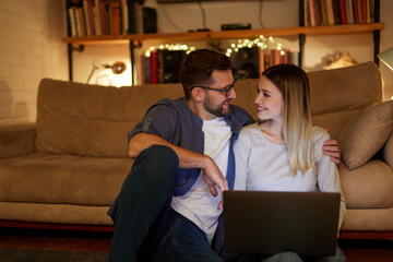 Young couple spending evening at home using laptop