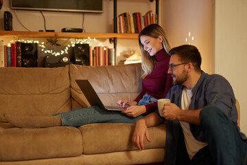 Young couple spending evening at home using laptop