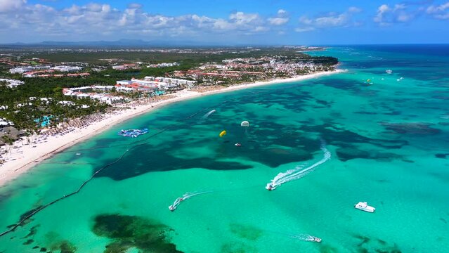 Aerial view of turquoise caribbean sea coast with all Inclusive resorts. Tourists having fun and enjoy water activities Parasailing. Best beach in Punta cana