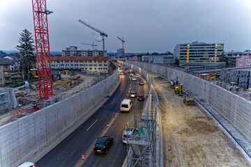 Heavy traffic at highway enclosure construction site at City of Z&uuml;rich district Schwamendingen on a gray and cloudy winter evening. Photo taken March 1st, 2023, Zurich, Switzerland.