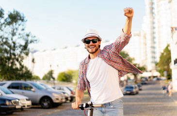 Young handsome man riding an electric scooter on vacation, having fun. Ecological transportation concept.