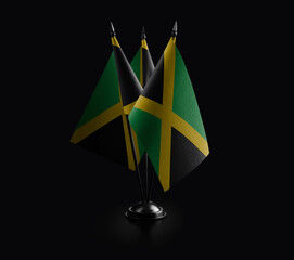 Small national flags of the Jamaica on a black background