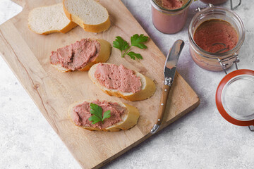 Homemade chicken liver pate on fresh french white wheat baguette slices on wooden plate, glass...