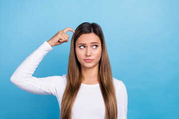 Fototapeta na wymiar Photo of doubtful unsure lady dressed white shirt finger head looking empty space isolated blue color background