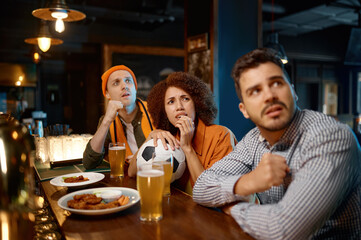 Group of worried friends watching favorite team at sports bar