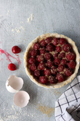 Homemade sweet cherry pie in a making. Close up photo of fruit tart on light grey table. 