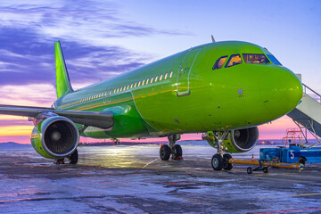 Fototapeta na wymiar Close-up with high detail of a large wide-body passenger aircraft standing in the airport parking lot during ground handling at night