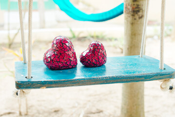 Close up of two red hearts on wooden table swing.