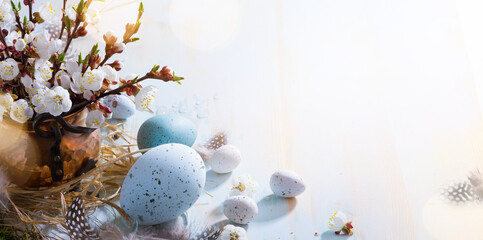 Happy Easter;  Easter eggs and natural sprig flowers on blue table background