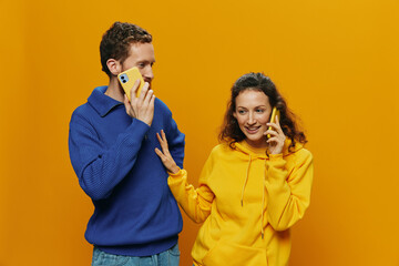 Woman and man cheerful couple with phones in hand talking on cell phone crooked smile cheerful, on...