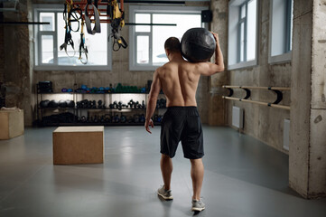 Fototapeta Portrait of male athlete holding med ball on shoulder after functional training obraz