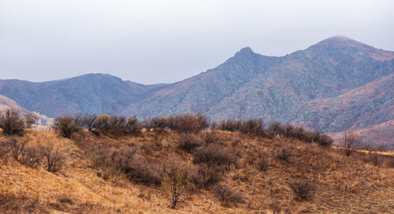 Misty rainy autumn mountain landscape in the morning. View of the misty mountain slopes in the distance. Morning foggy hills. Autumn in remote foothills in northern China.