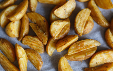 Potatoes baked with rosemary herb on parchment paper in stove for dinner