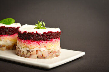 Close up to Traditional holiday layered fish salad Herring under fur coat served in culinary rings. serving size of salad with marinated herring fish, onion, grated potato, beetroot, mayonnaise on top