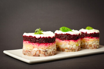 Close-up to Traditional holiday layered fish salad Herring under fur coat served in culinary rings. Three portions of salad in focus and out of focus