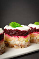Close up to Traditional holiday layered fish salad Herring under fur coat served in culinary rings. Copy space image with text space. Russian salad with beetroot, potato, onion, fish and mayonnaise