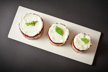 Top view of Traditional holiday layered fish salad Herring under fur coat served in culinary rings. Copy space image with text space. Russian salad with beetroot, potato, onion, fish and mayonnaise