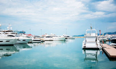 Fototapeta premium Yacht parking in harbor, harbor yacht club. Beautiful Yachts in blue sky background. Luxury super yacht marina and sailing boats.