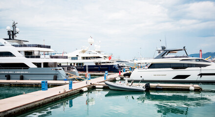 Fototapeta premium Yacht parking in harbor, harbor yacht club. Beautiful Yachts in blue sky background. Luxury super yacht marina and sailing boats.
