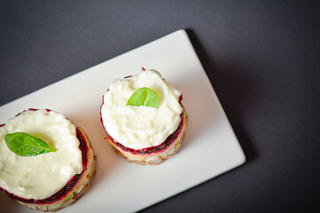 Top view of Traditional holiday layered fish salad Herring under fur coat served in culinary rings. Copy space image with text space. Russian salad with beetroot, potato, onion, fish and mayonnaise