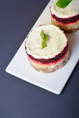 Top view of Traditional holiday layered fish salad Herring under fur coat served in culinary rings. Copy space image with text space. Russian salad with beetroot, potato, onion, fish and mayonnaise