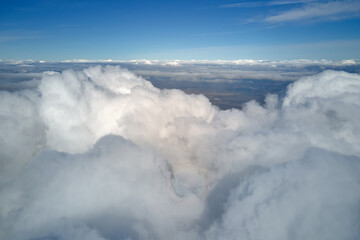 Aerial view from airplane window at high altitude of earth covered with white puffy cumulus clouds